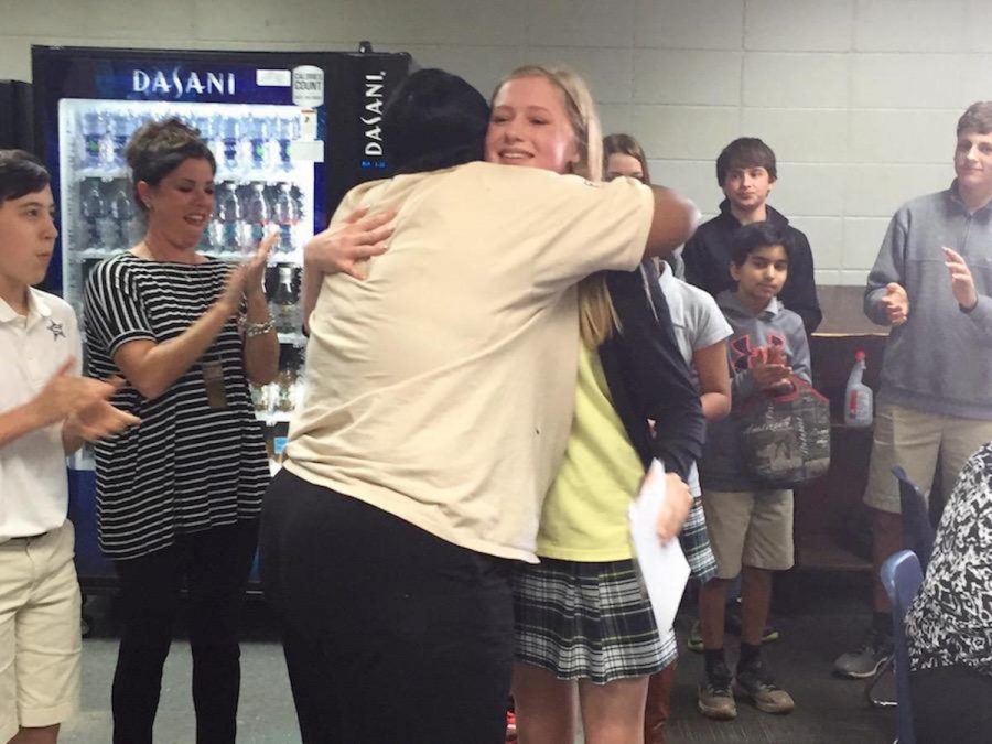 Keisha Tucker, a member of the FLIK lunchroom staff, gives Kacey Cross a hug as students and teachers applaud.