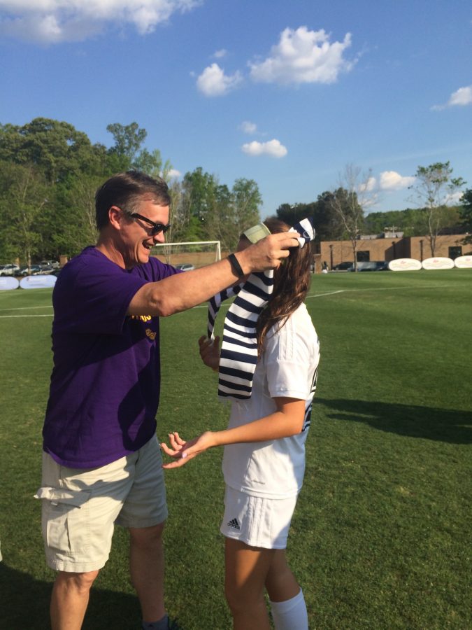 Soccer parent Johnny Peterson gives his daughter Ellie her scarf after the game against Dooly County