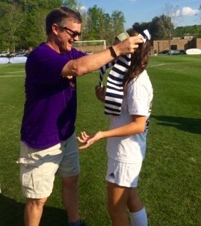 Soccer parent Johnny Peterson gives his daughter Ellie her scarf after the game against Dooly County
