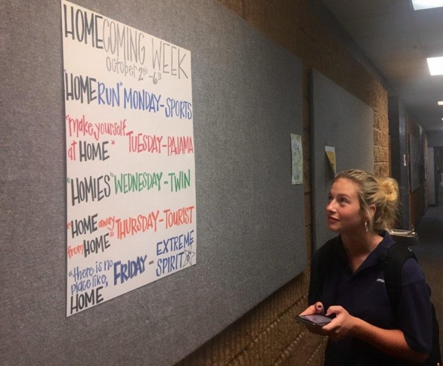 Senior Tori Dover, a member of this years homecoming court, looks at the poster in the main hallway with details of Homecoming Week.