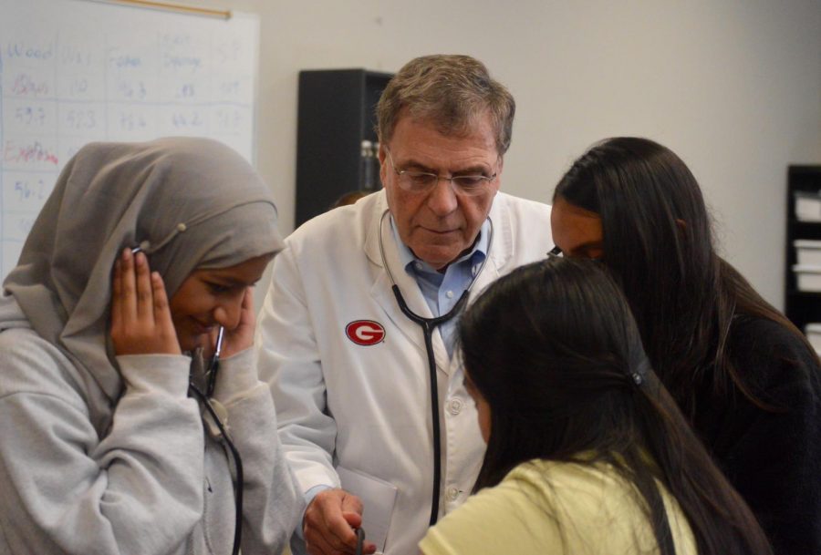 Stratford students (L-R) Zuna Shabbir, Vivian Duong and Cap Patel are shown how to take blood pressure by Dr. Bill Brooks, who has been practicing medicine for more than 50 years