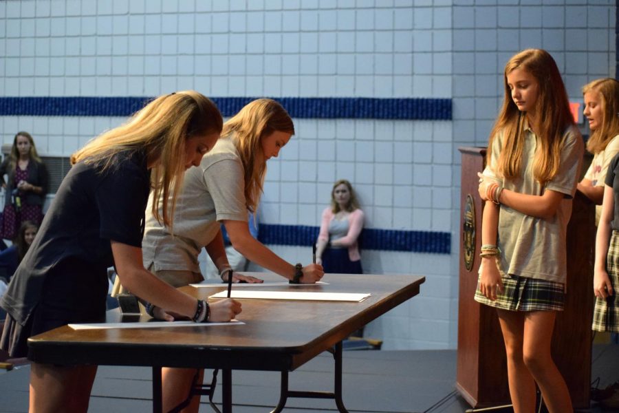 Freshmen Harley Anne Shurling and Carly Blackwood sign the honor code as Katie Beth Powers looks on