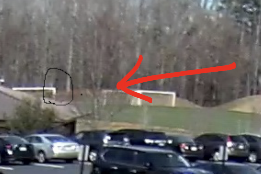 An arrow points to the black bear (circled) on Thursday at the far end of the soccer practice field. The image is a screen shot from a security camera at the Cantrell Lower School.