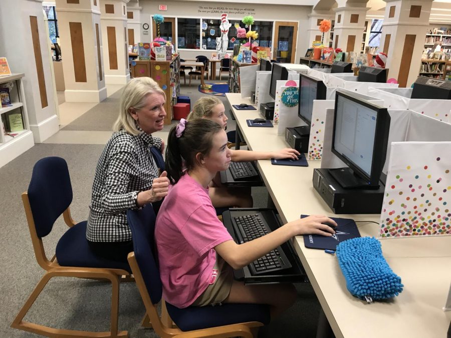 Ms. Davis helps lower school students with computers. 